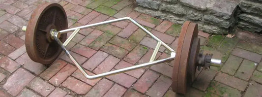 Trap bar with weight plates on a brick surface, illustrating its design and function for weight training.